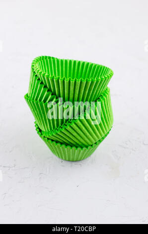 Brightly green colored paper baking cups for cupcakes or muffins on light grey conkrete background, copy space Stock Photo