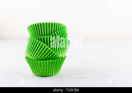 Brightly green colored paper baking cups for cupcakes or muffins on light grey conkrete background, copy space Stock Photo