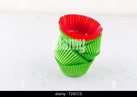 Brightly green and red colored paper baking cups for cupcakes or muffins on light grey conkrete background, copy space Stock Photo