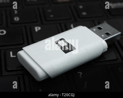 USB flash drive with padlock icon, on a laptop keyboard. Private key for data security. Secure and encrypted removable storage device. Stock Photo