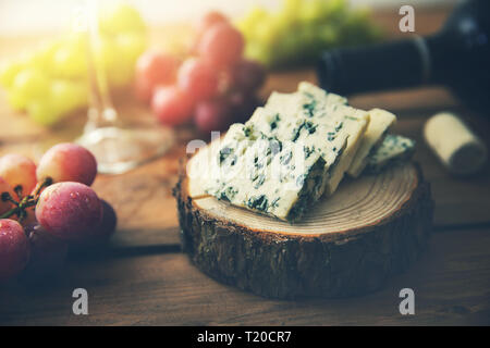dor blue cheese on wood log slice with grapes and wine bottle Stock Photo