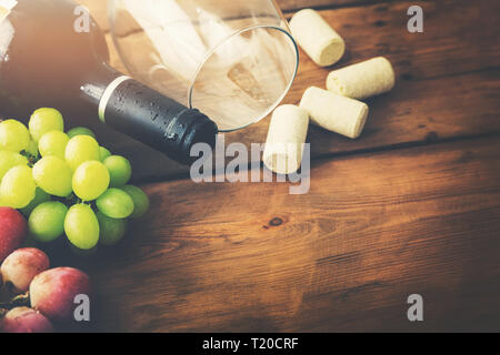 red wine bottle with glass and grapes on wooden background Stock Photo