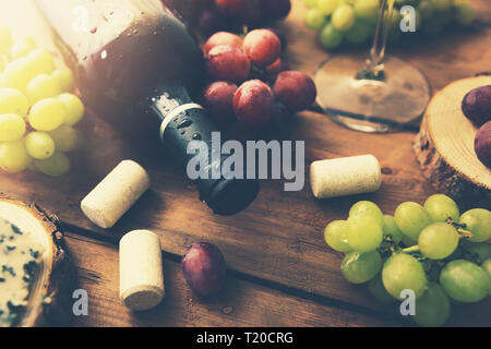 red wine bottle with grapes on old wooden background Stock Photo