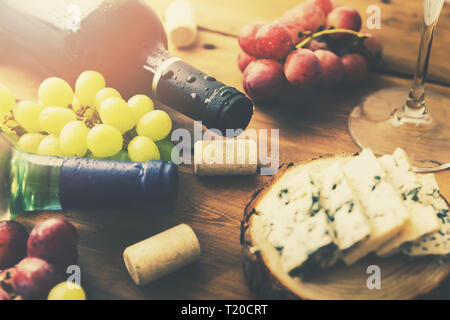 wine bottles grapes and cheese on old wooden table Stock Photo