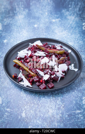 Close view of beetroot coconut side dish. Indian beetroot poriyal on a black plate and a grey background.