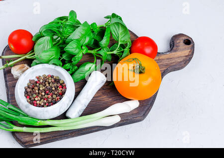 Ripe red and yellow tomatoes, green onion and basil, garlic, salt  and spices on a light grey stone  background. Top view, Copy space. Stock Photo