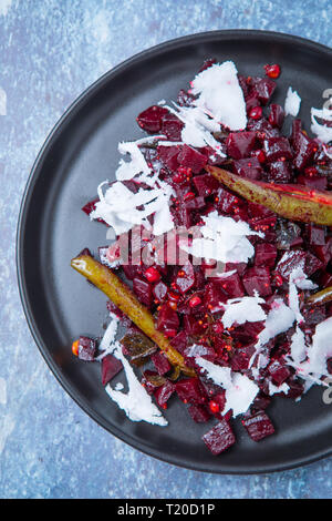 Close up of Indian beetroot poriyal topped with green chillies on a grey kitchen top. Close up sliced beetroot.