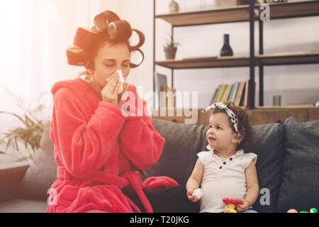 Young mother old is experiencing postnatal depression. Sad and tired woman with PPD. She does not want to play with her daughter. The woman is sick an Stock Photo