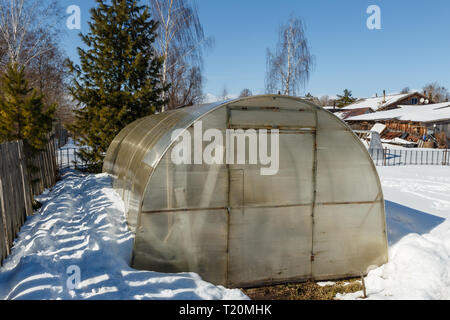 Small greenhouse with a metal frame covered with polycarbonate. greenhouse in winter Stock Photo