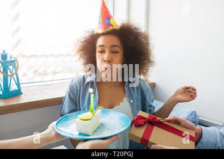 A picture of birthday girl blowing up the candle and getting a present from her friends Stock Photo