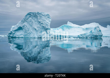 an amazing iceberg in the ice graveyard in Antarctica causing a beautiful reflection on the surface of the water while in a zodiac Stock Photo
