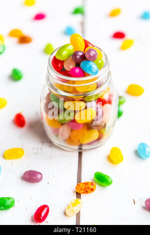Glass of colourful sweet jellybeans on white wood Stock Photo