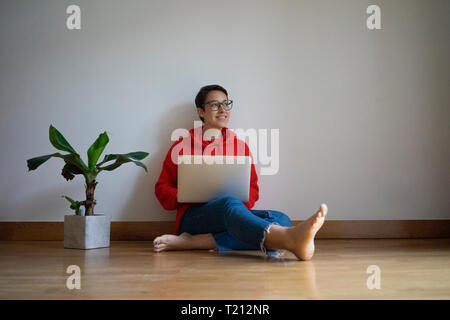 Young woman sitting on floor, using laptop Stock Photo