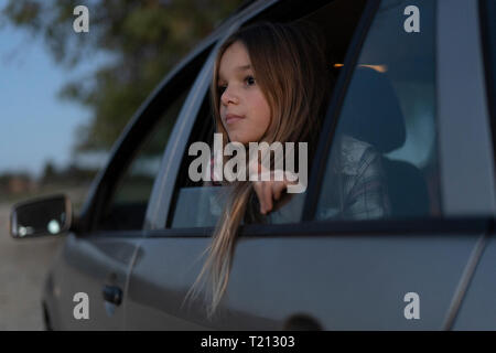 Girl looking out of car window in the evening Stock Photo