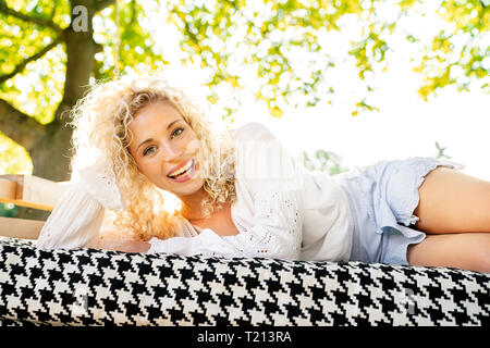 Happy young woman lying on a bed in garden Stock Photo