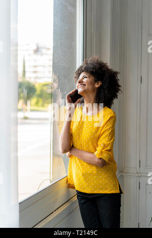 Woman standing at the window, talking on the phone Stock Photo