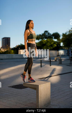 Sporty young woman standing on concrete block in the city Stock Photo
