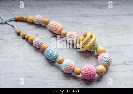 Necklace made from knitted beads and toys for the baby sitting in a sling. Knitted beads. Sling necklace. Stock Photo