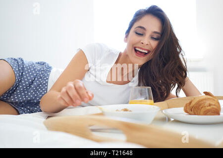 Young woman enjoying breakfast in bed Stock Photo