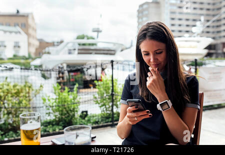 Young beautiful woman using her smartphone on a terrace Stock Photo