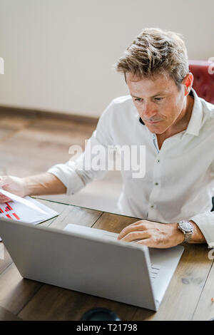 Focused businessman using laptop at desk Stock Photo
