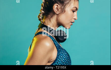 fitness woman in sportswear and headphones. Side view of caucasian sports woman on blue background Stock Photo