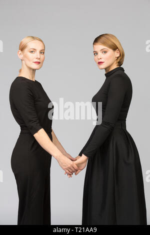 Studio portrait of mother and adult daughter holding hands Stock Photo