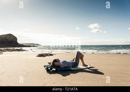 Young woman on the beach, relaxing on surfboard Stock Photo