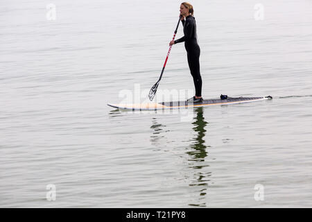 Branksome Dene, Poole, Dorset, UK. 30th Mar, 2019. UK weather: hazy morning sunshine and cooler of late, but doesn't stop visitors heading to the seaside at Branksome Dene. Woman paddleboarding. standup paddleboarder standup paddle boarder Credit: Carolyn Jenkins/Alamy Live News Stock Photo