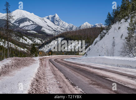 Scenic Winter Drive in Montana:  A snowy mountain road curves through a portion of Glacier National Park that remains open all year. Stock Photo