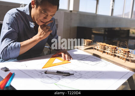 Male architect working on blueprint at desk in a modern office Stock Photo