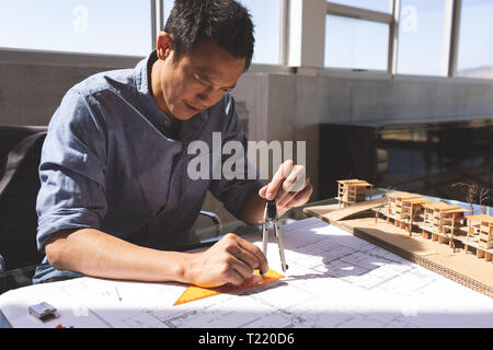Male architect working on blueprint at desk in a modern office Stock Photo