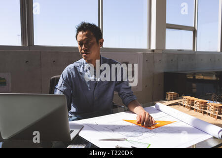 Male architect using laptop while working on blueprint Stock Photo