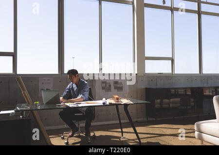 Male architect sitting at desk and working on laptop Stock Photo