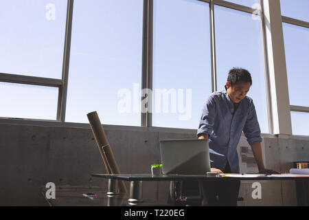 Male architect standing at desk and looking blueprint in a modern office Stock Photo
