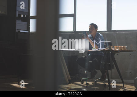 Male architect using mobile phone at desk in a modern office Stock Photo