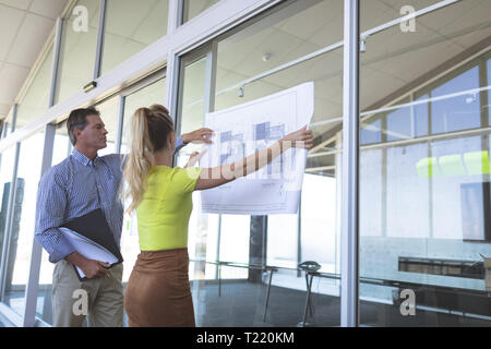 Male and female architects discussing over blueprint in the office Stock Photo