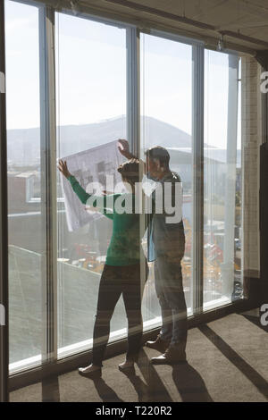 Architects discussing over blueprint in office Stock Photo