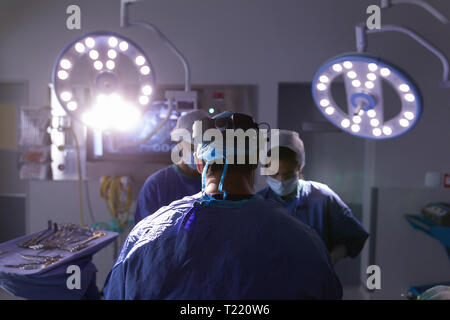 Surgeons performing operation in operating room at hospital Stock Photo