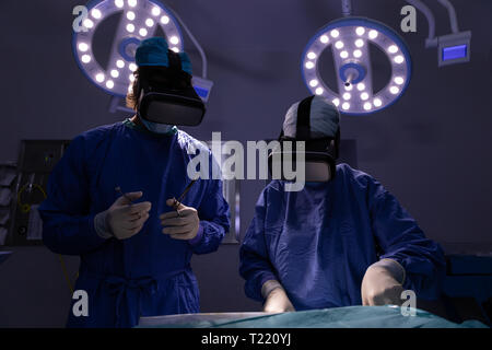 Surgeons using virtual reality headset during surgery in operating room at hospital Stock Photo