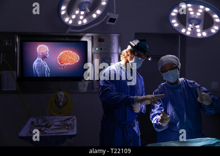 Surgeons talking with each other during surgery in operating room Stock Photo