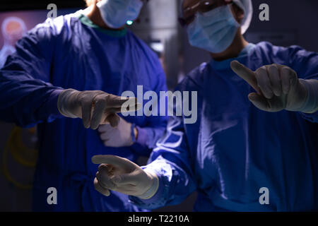 Surgeons talking with each other during surgery in operating room at hospital Stock Photo