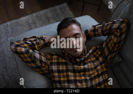 Man lying on sofa at home Stock Photo