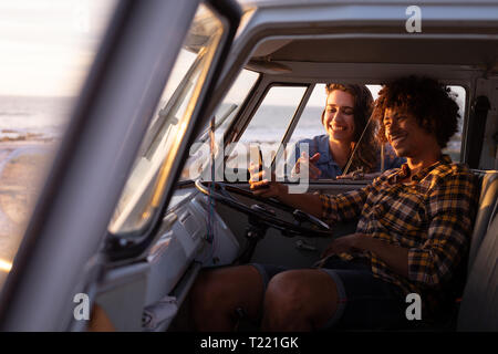 Man in a camper van taking a selfie with a woman leaned outside of window Stock Photo