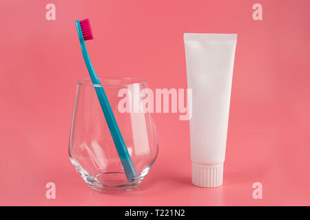 Toothbrush in glass isolated on pink background with toothpaste tube Stock Photo