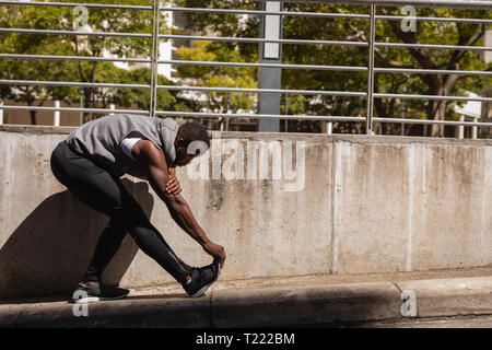 Man doing stretching exercise on side walk Stock Photo