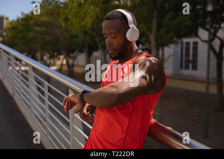 Man with headset looking at smart watch while standing by railing Stock Photo