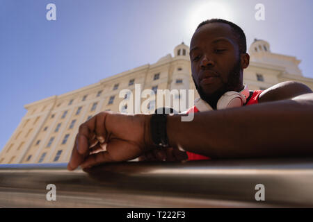 Man with headset looking at smart watch while standing by railing Stock Photo