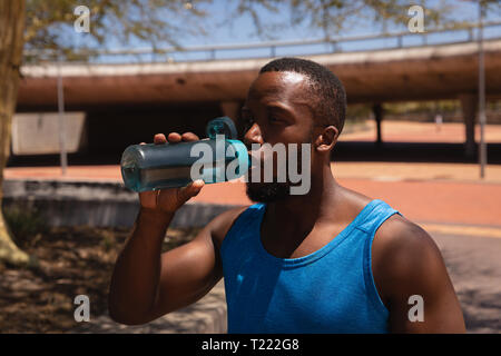 Man drinking water while standing on street on a sunny day Stock Photo