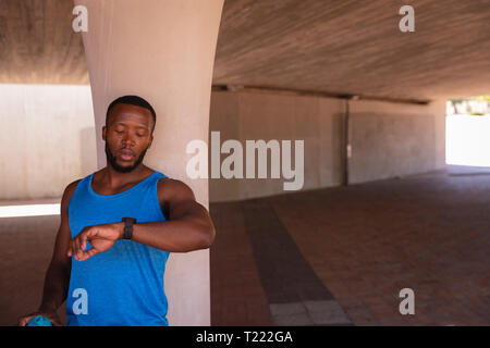 Man looking at smart watch while standing under the bridge Stock Photo